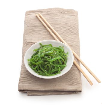 White bowl with chuka seaweed on the napkin with wooden chopsticks