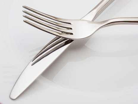 Silverware: fork and knife on white empty plate