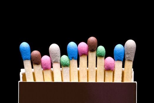 Multi-coloured matches in a box (a black background).