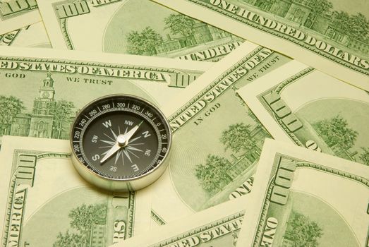 Compass on a background of dollars (it is a lot of money).