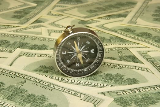 Compass on a background of dollars (it is a lot of money).