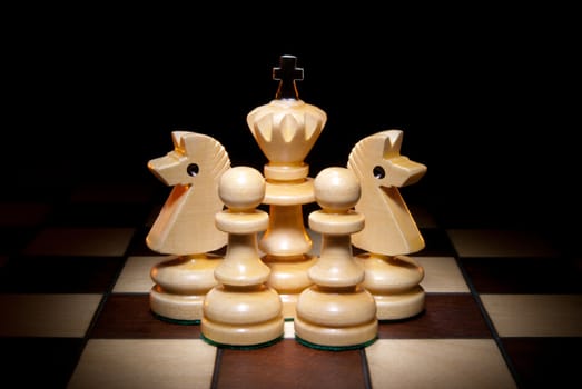 Chessmen on a chess board. A dark background and art illumination.