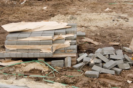 Elements of paving slabs stacked on a pallet in a stack and heap on the ground lying around on the street