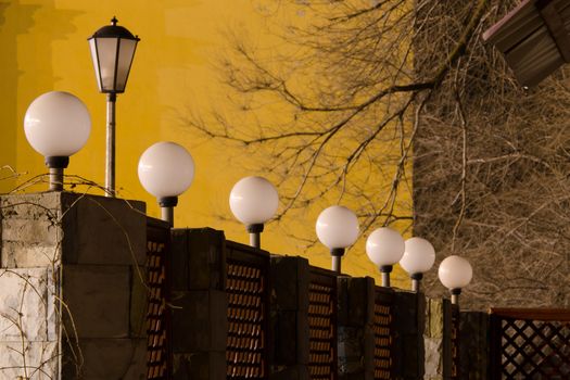 Number of round street lamps not burning on the fence in the evening