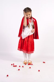 Little girl in costume red cap with a cherry on earth