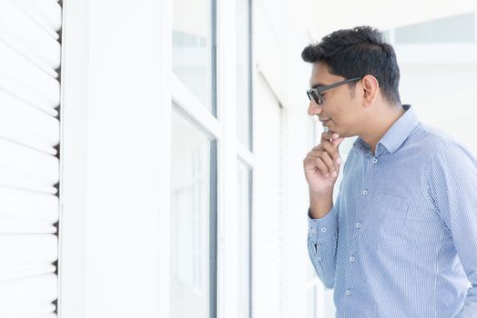 Young man looking through the window and thoughtful.