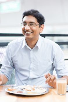 Asian Indian businessman eating food at cafeteria.