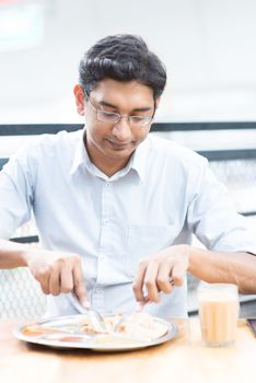 Asian Indian businessman having meal at cafeteria.