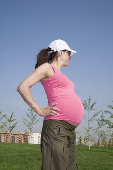 pregnant woman with pink shirt posing at park