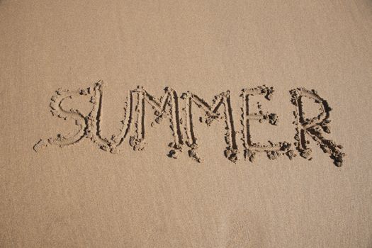 summer word written on brown sand ground low tide beach ocean seashore in Spain Europe