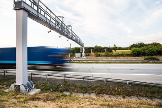 truck passing through a toll gate on a highway (motion blurred image; color toned image)