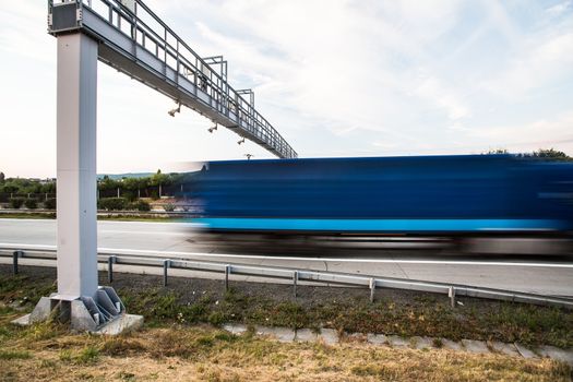 truck passing through a toll gate on a highway (motion blurred image; color toned image)