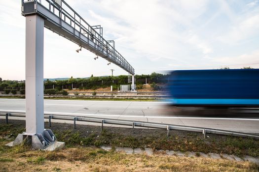 truck passing through a toll gate on a highway (motion blurred image; color toned image)