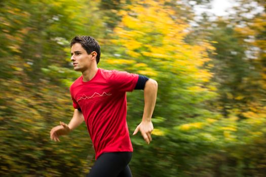 Young man running outdoors in a city park on a fall/autumn day (motion blurred image)