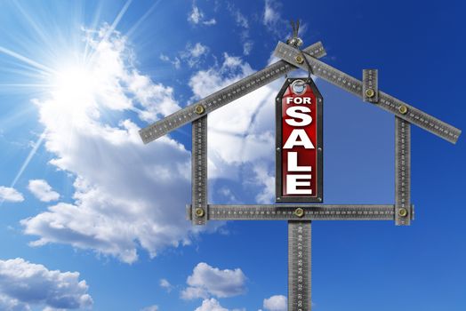 Grey metallic meter ruler in the shape of house and label with text for sale. For sale real estate sign on blue sky with clouds and sun rays
