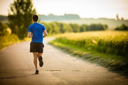 Male athlete/runner running on road - jog workout well-being concept