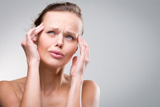 Gorgeous young woman with severe headache/migraine (color toned image)