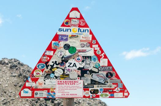 SWARTBERG PASS, SOUTH AFRICA - JANUARY 2, 2015: Road sign cluttered with stickers from all over the world near the top of the pass.