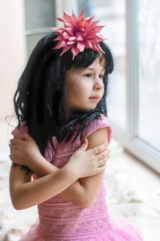 portrait of a six-year girl  in the window in the afternoon.