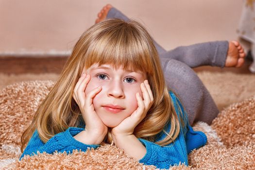 little girl with funny tails is lying on the white carpe