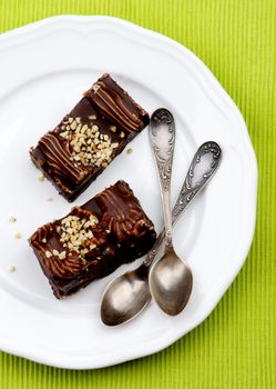 Chocolate Mocha Cakes Mocha Frosting, Cream and Nuts on White Plate with Silver Tea Spoons closeup