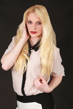 Portrait of a young blond woman with long hair, red lipstick, fashionably dressed on black background.
