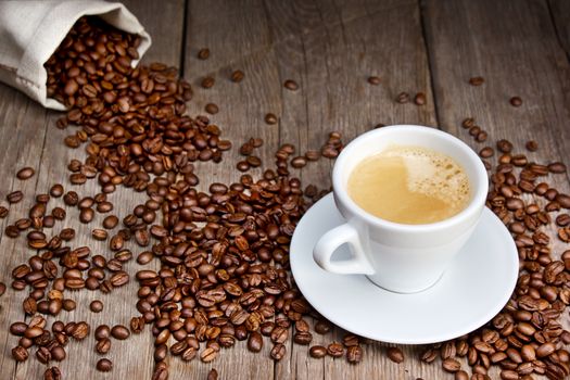 Coffee cup with beans on wooden background