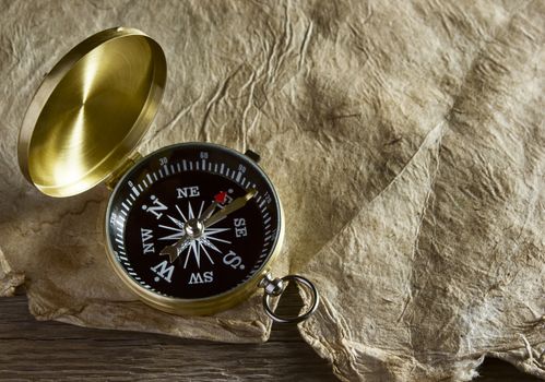 Old compass and paper on wooden background
