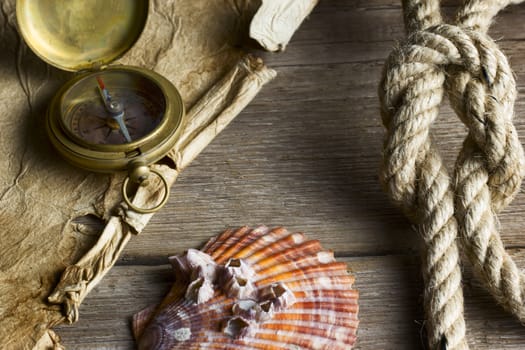 Old compass, rope and shell on wooden background