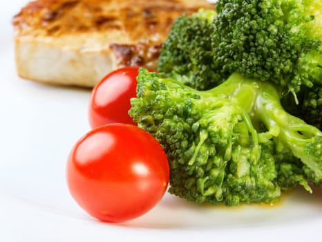 Broccoli with meat and cherry tomatoes on white plate