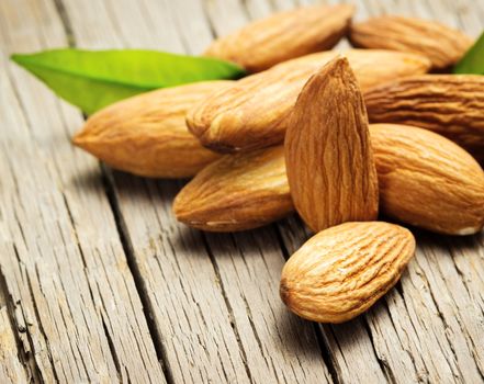 Almonds with leaves on wooden background