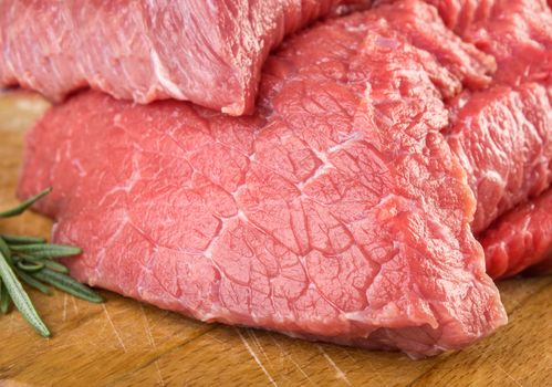 Raw meat with rosemary on cutting board