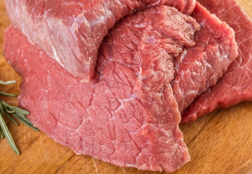 Raw meat with rosemary on cutting board