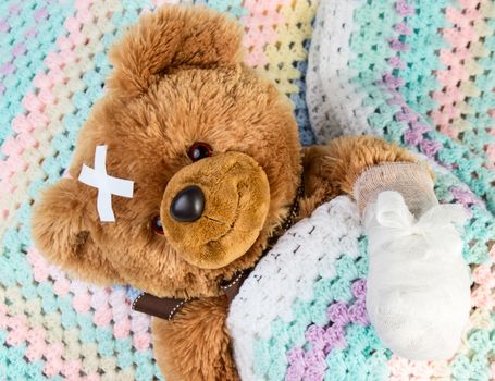 Sick teddy bear with bandage in a bed