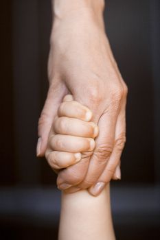 Small children's hand lies on a hand mom (focus on the mother's middle fingers)