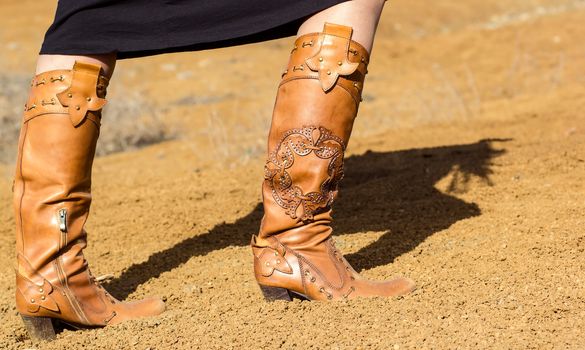 Woman shoed in boots walking on sand