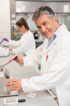 Pharmacist using press to make pills at the laboratory
