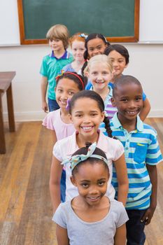 Cute pupils smiling at camera in classroom at the elementary school