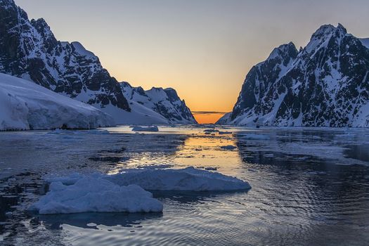 Tourist icebreaker in the dramatic scenery of the Lemaire Channel on the Antarctic Peninsula in Antarctica. Photo taken at 3am by the light of the Midnight Sun.