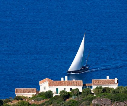Greek yacht with white sail swim to the shore of Crete. Crete, Greece, Europe.