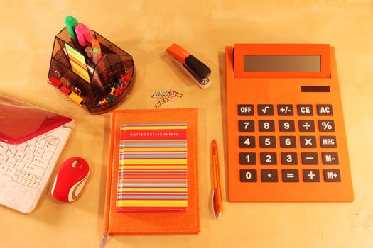 Calculator, daily planner and orange colored stationery