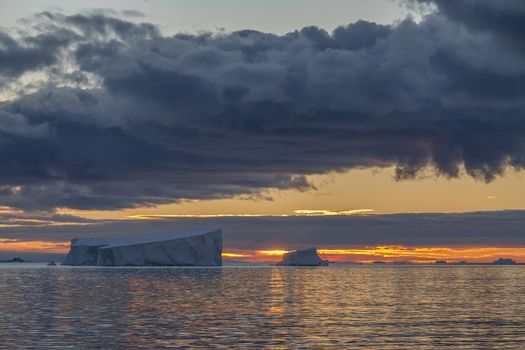 The Midnight sun over the icebergs of the Drake Passage near the Antarctic Peninsula in Antarctica. 