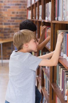 Cute pupils looking for books in library at the elementary school