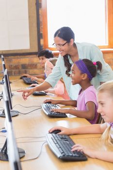 Cute pupils in computer class with teacher at the elementary school