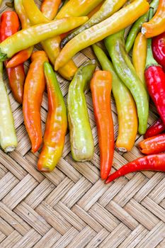 pile of yellow and red thai goat pepper on bamboo plate