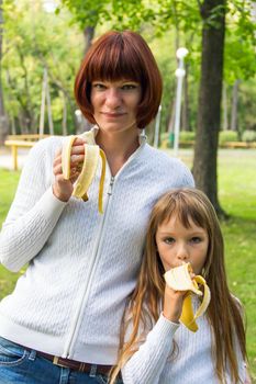 Photo of mother and daughter eating banana