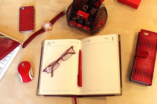 Open daily planner, computer, cell phone, business card holder, sunglasses, watches and stationery in red style