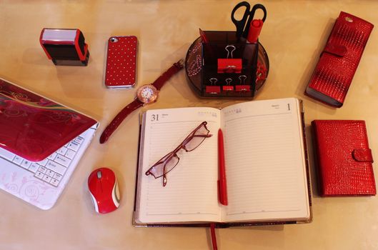 Open daily planner, computer, cell phone, business card holder, sunglasses, watches and stationery in red style