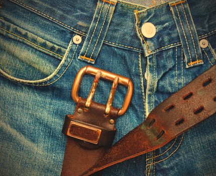 Vintage leather belt with metal buckle on old blue jeans. instagram image retro style