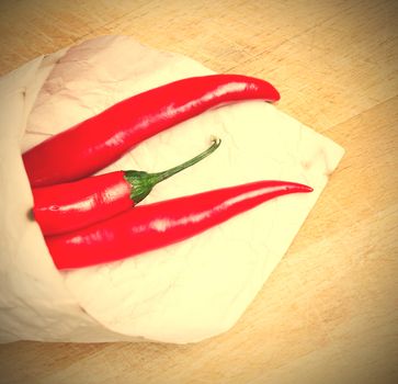 red hot chili peppers in paper bags on a wooden background. instagram image style